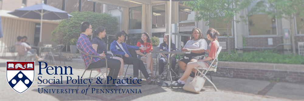 Students chat with each other at a table outside of the Caster building